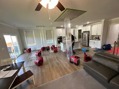 Open-plan Garner area living room with red air movers on the floor and a section of ceiling opened for drying