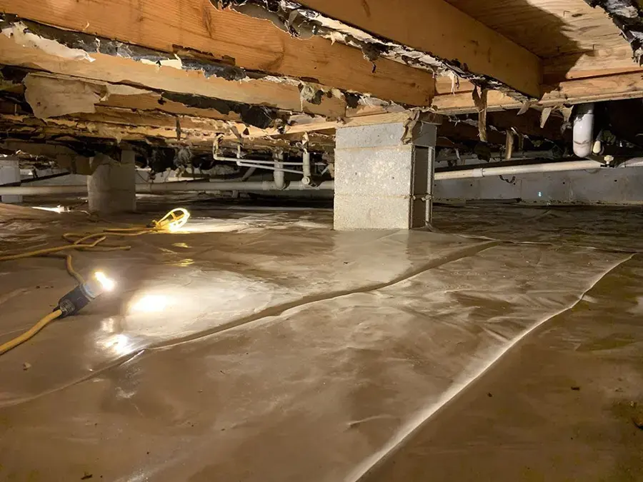 Flooded crawl space with water standing over the plastic ground cover under a home